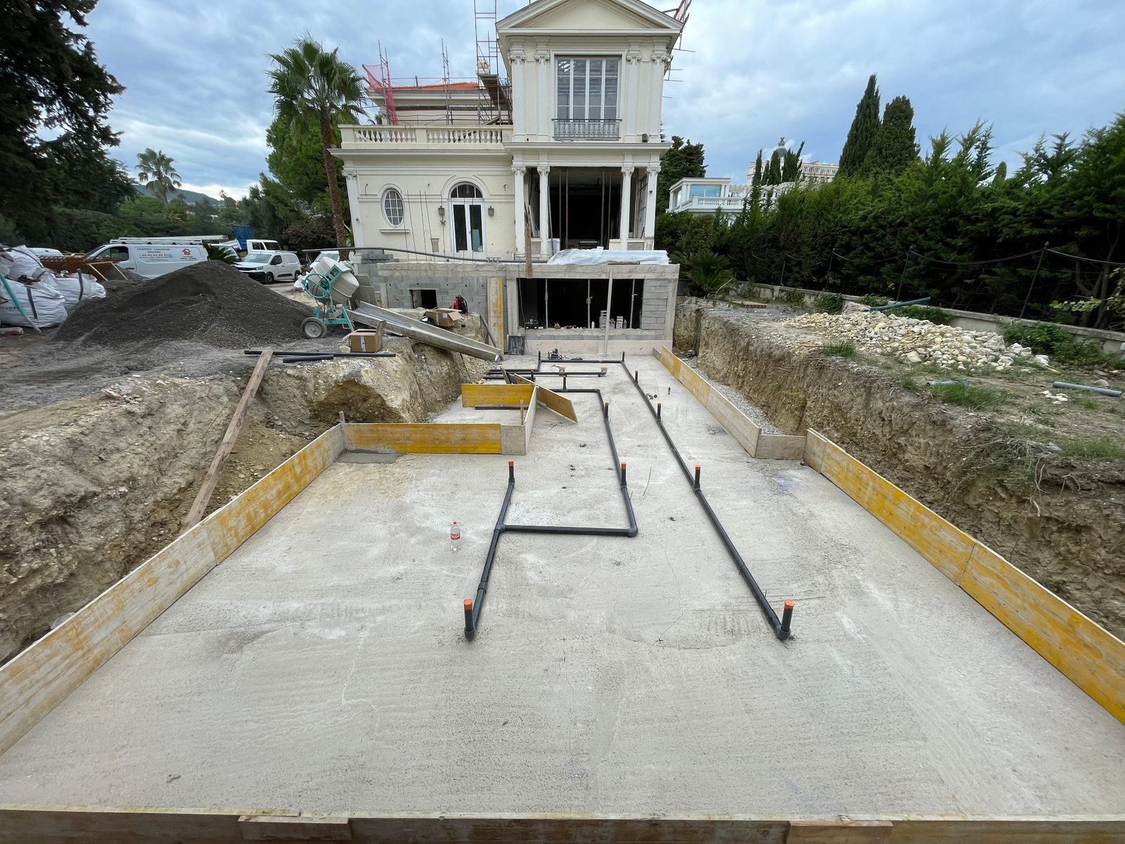 Fond de la piscine miroir en chantier avec les canalisations de l'hydraulique inversée posées sur le béton